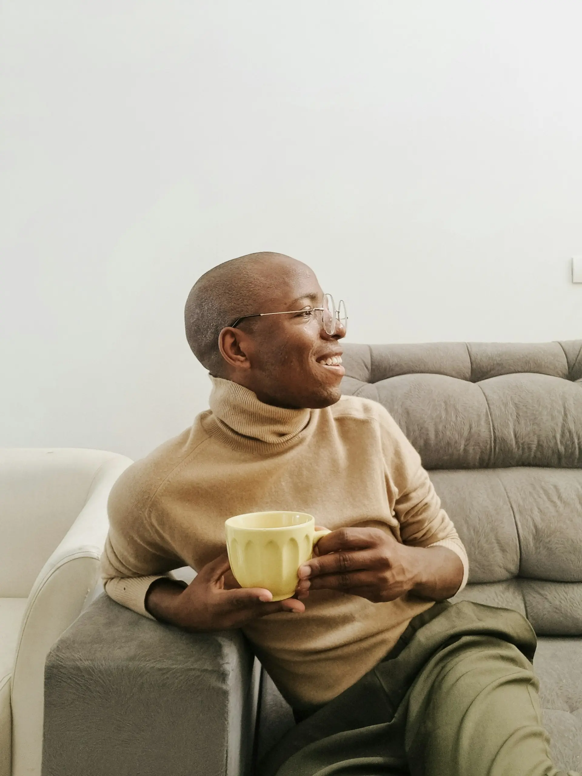 An older man at home on the sofa, relaxed, holding a cup of tea.