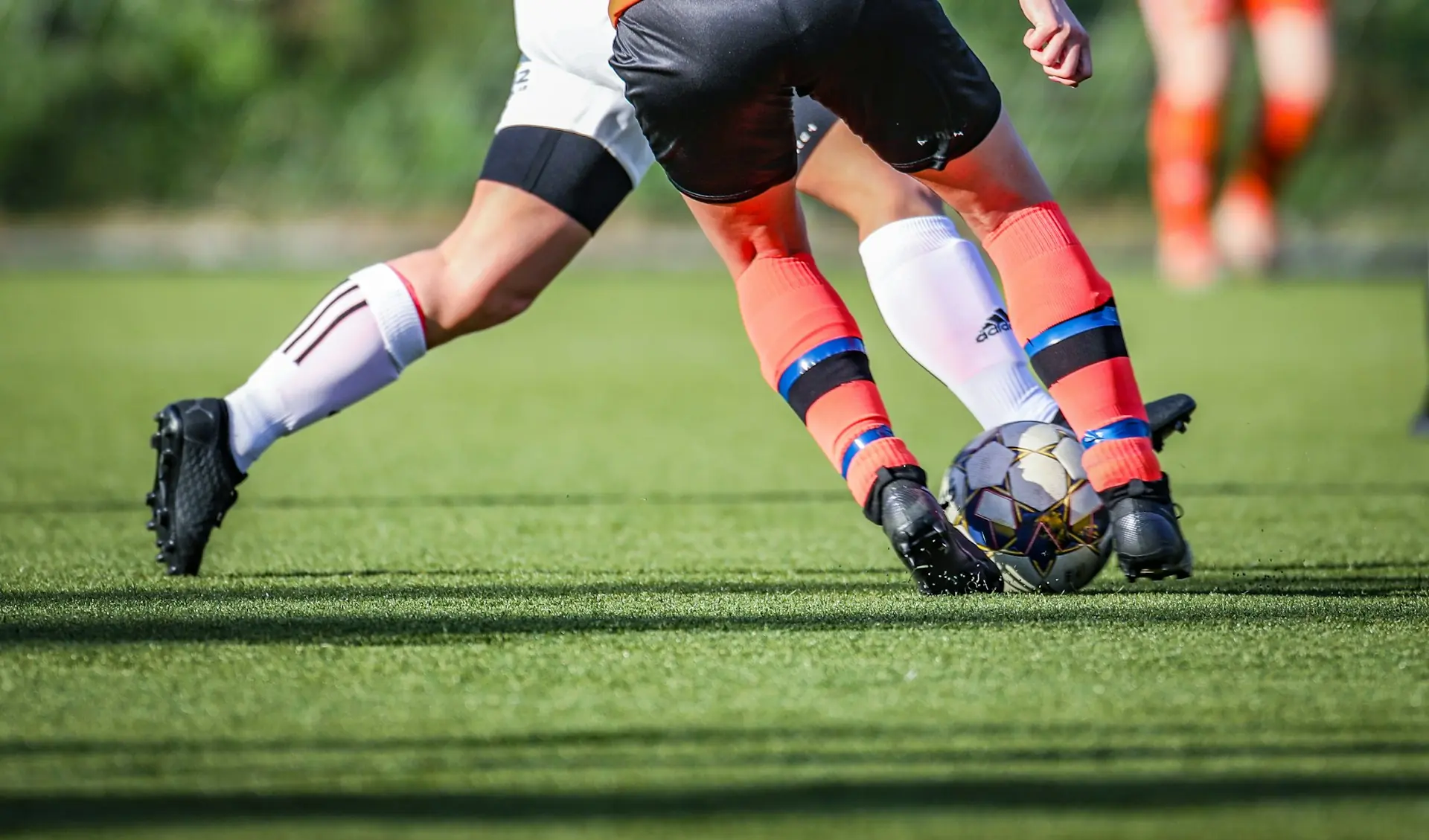 A player striking the ball on a green pitch.