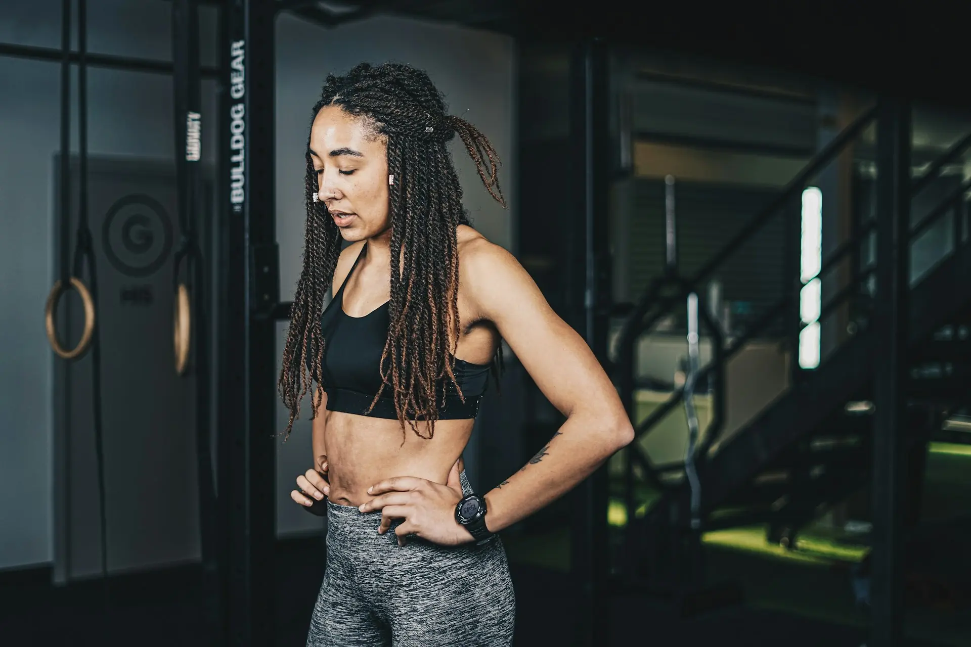 A woman with locs standing in a gym between sets.