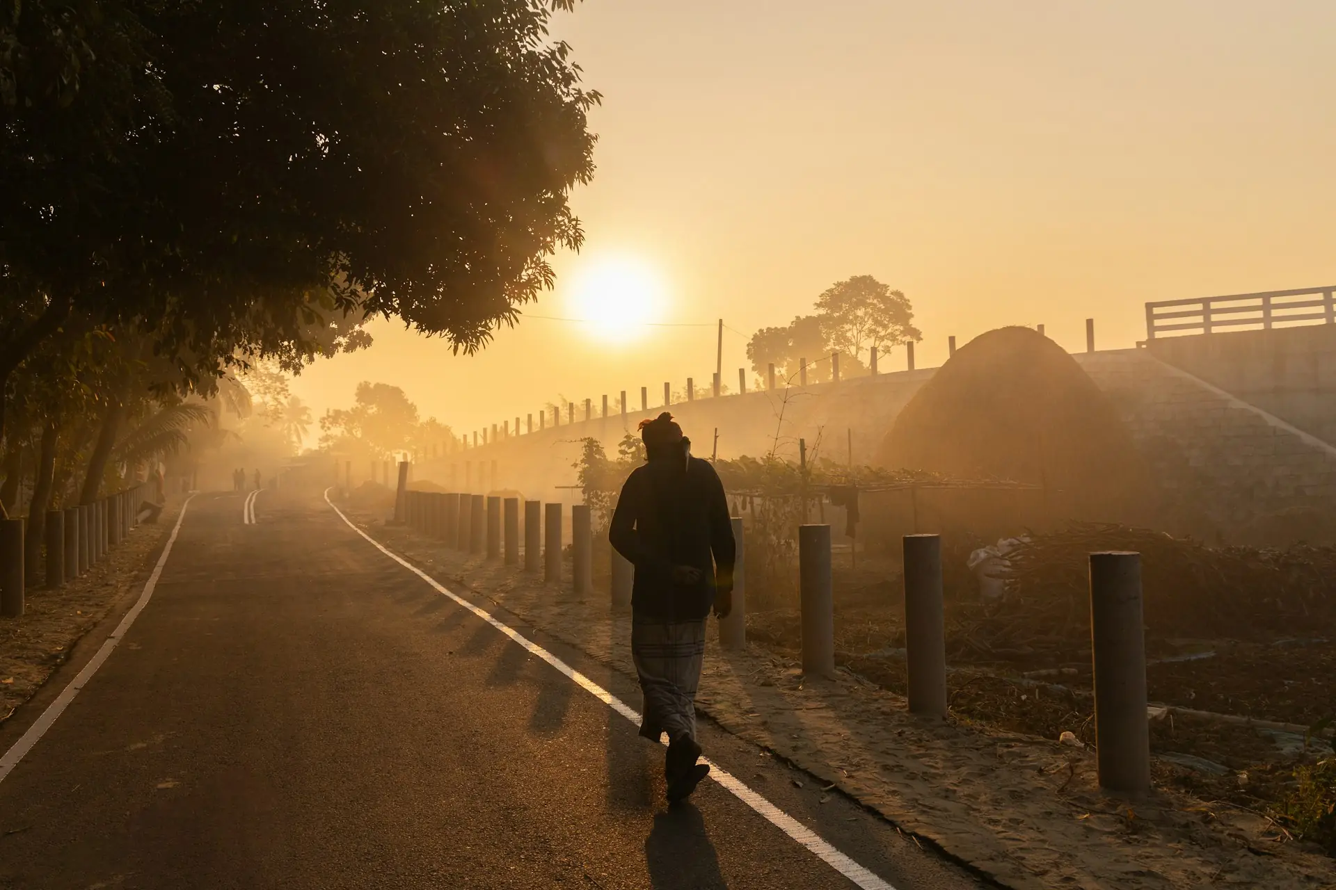 A runner on a misty road at sunrise, the light just breaking through.